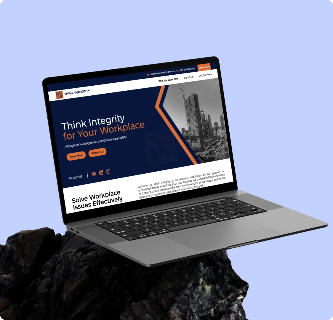 A laptop tilted on a rock, showing the homepage hero and the beginning of the section under it.