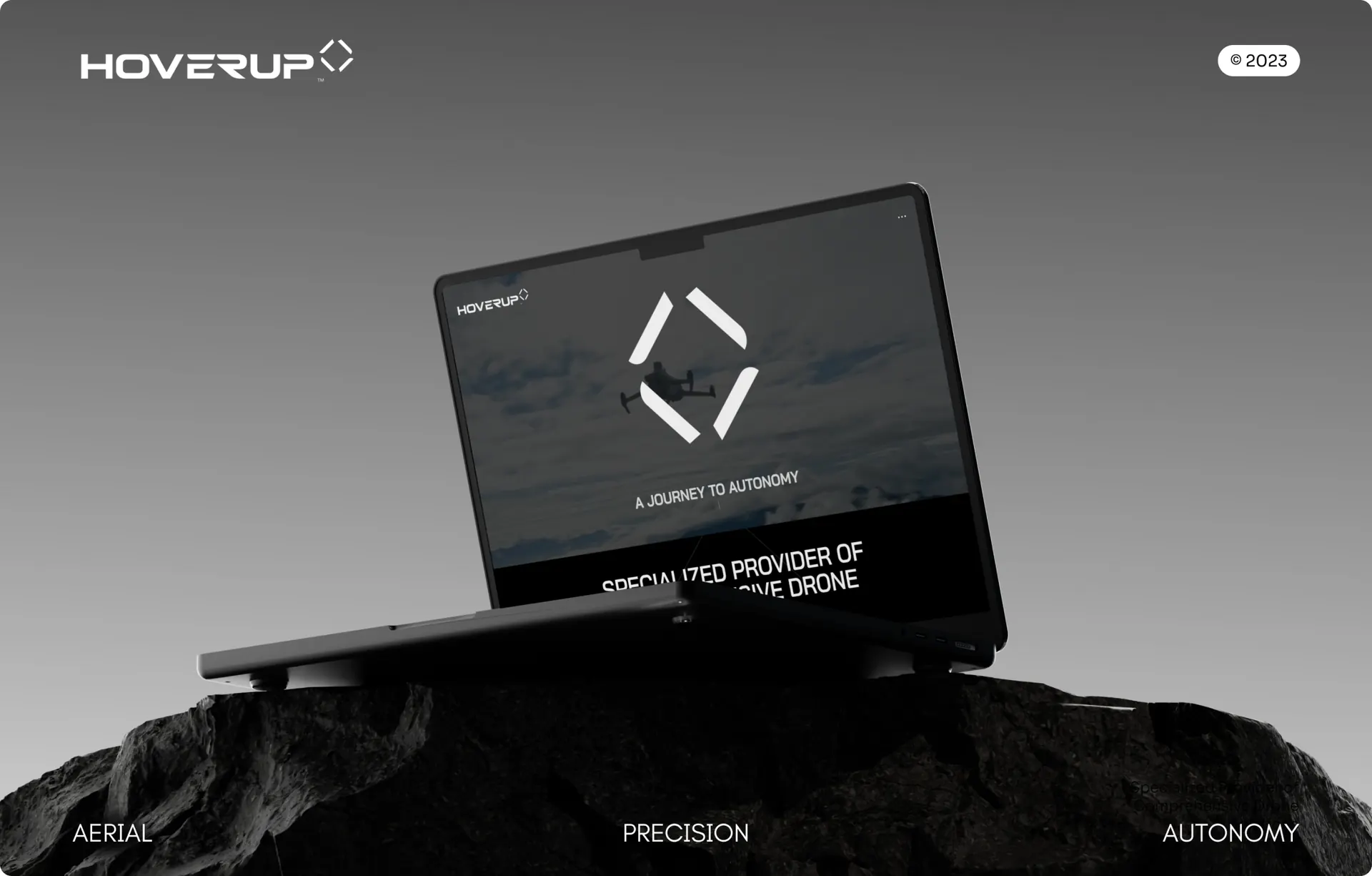 A laptop sitting on a rock, showing the home page with the drone logo over sky footage and the headline below it.