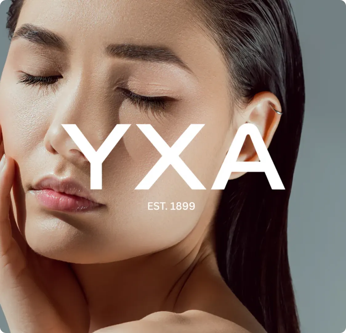 A close-up of a woman with her eyes closed touching her cheek, with the YXA wordmark laid across the middle.